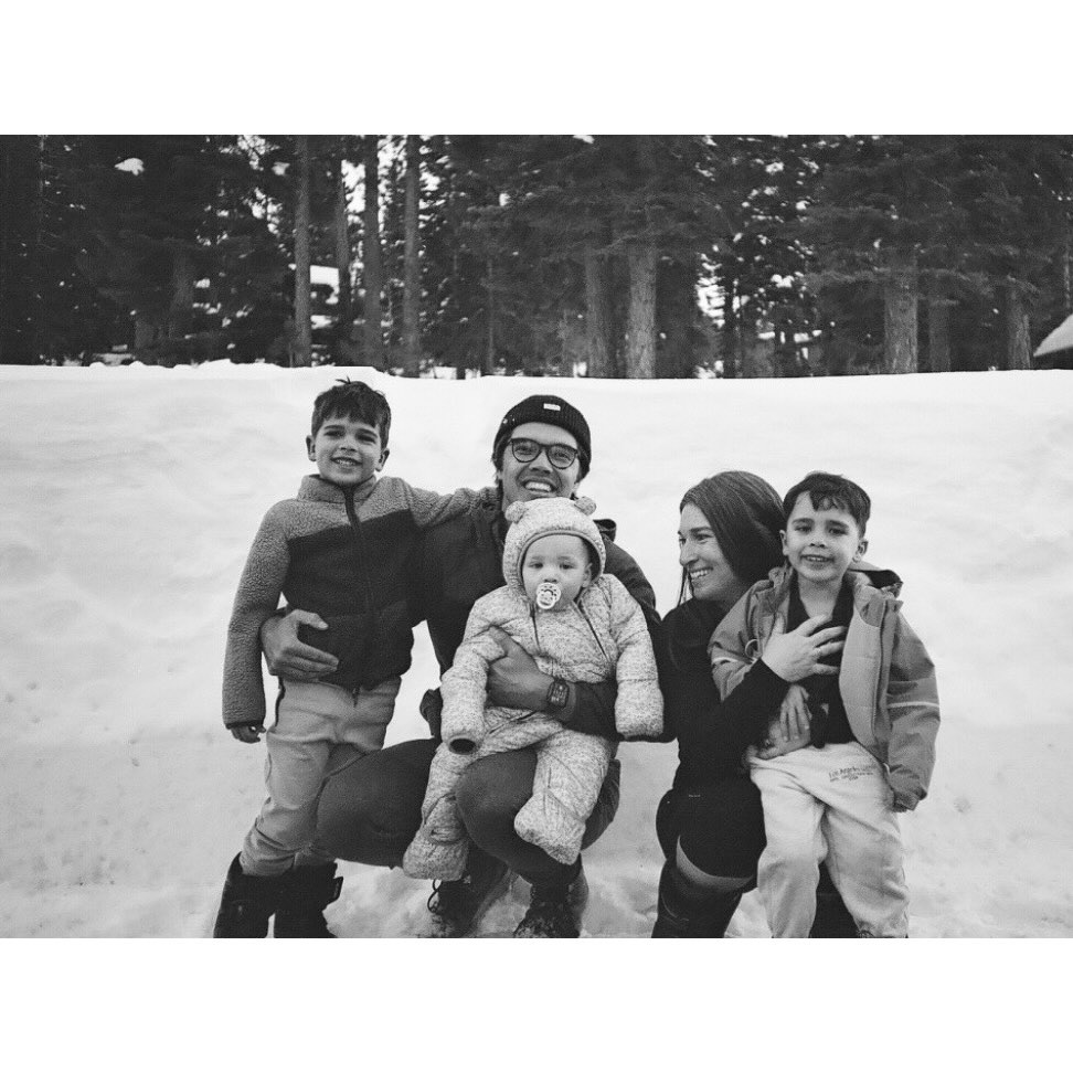 Ryan crouching in the snow with his three kids and partner, pine trees behind them